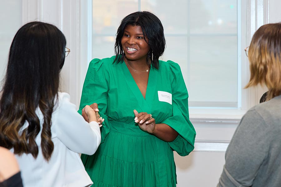 a community member in green dress shakes hands with a student