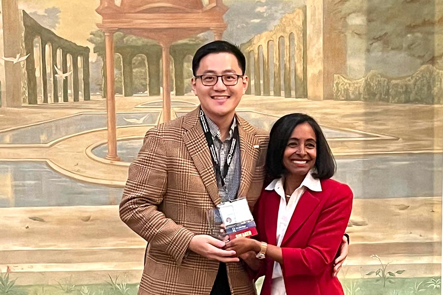 Tianyi Li holds an award with an ASPA professional in front of a backdrop
