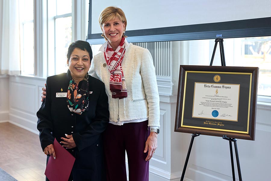 Dean Yelkur stands next to Chancellor Feyton next to an easel with Beta Gamma Sigma certificate
