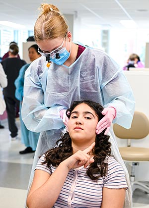 a TWU dental hygiene student checks a to child's jaw with both hands