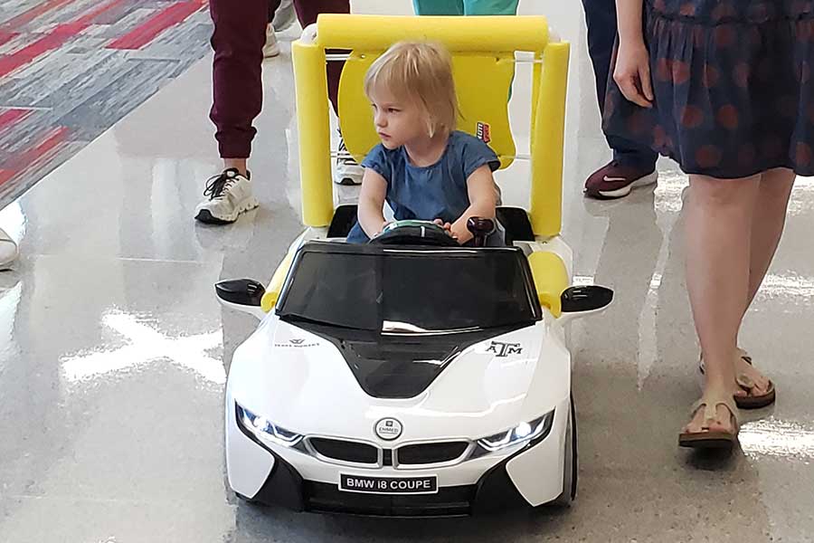 young child drives a small white electric car