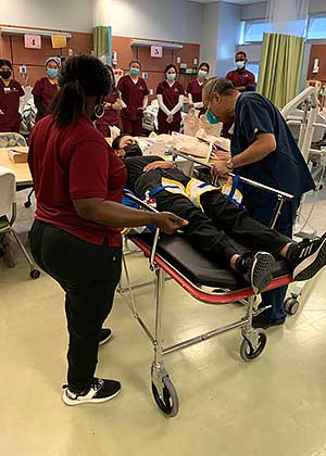 professor and student examine patient on gurney