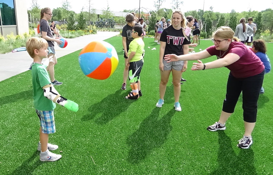 TWU student throws beach ball to boy.