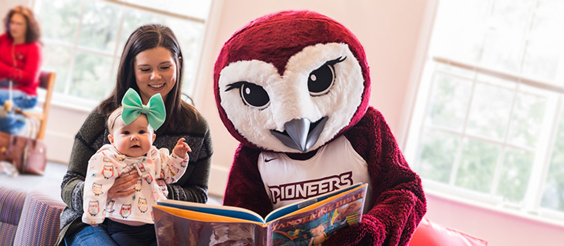 Oakley the Owl reads a picture book to a baby